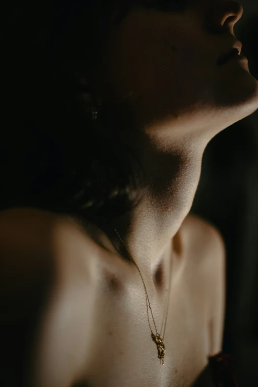 a woman with a necklace on a dark surface