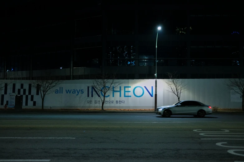 a lit up building at night with a wall with an ad in the street