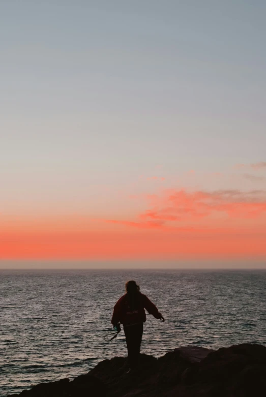 a person standing on top of a beach under a red sky