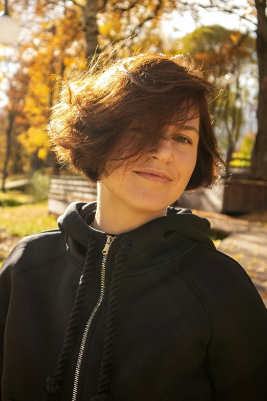 a woman is standing outside in the fall