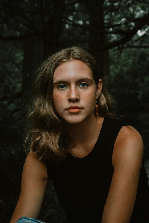 a woman with long brown hair sitting in the forest