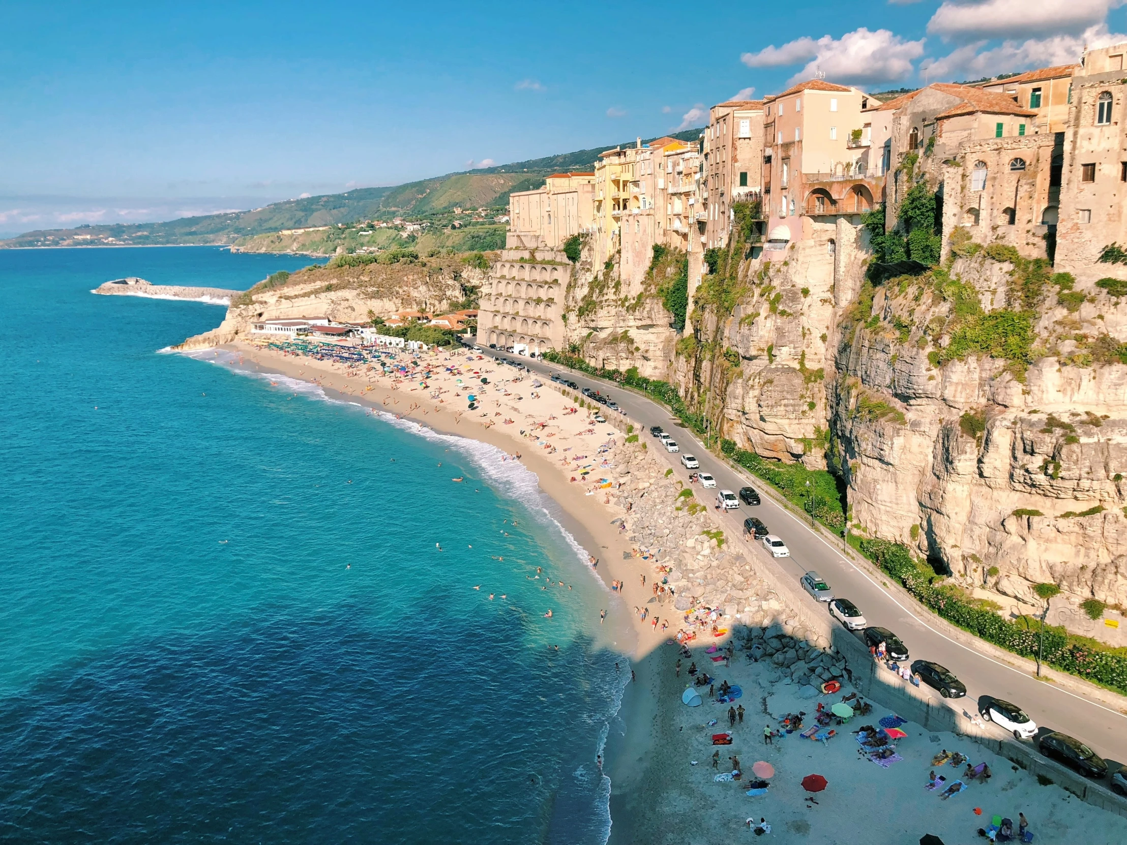 people walk on the sand next to the ocean and beach