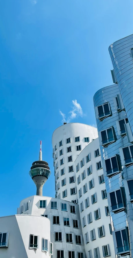 some tall white buildings with windows and a television tower in the background