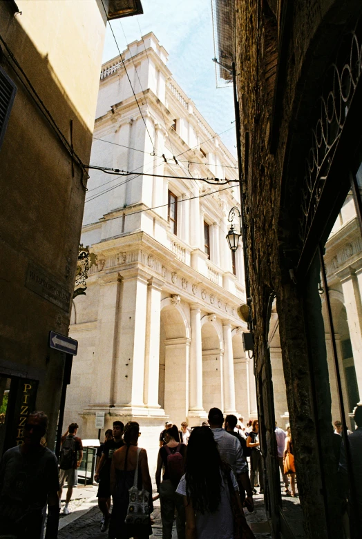 some people walking down the street and building with lots of windows