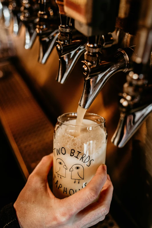 person pouring a glass at a bar with multiple taps