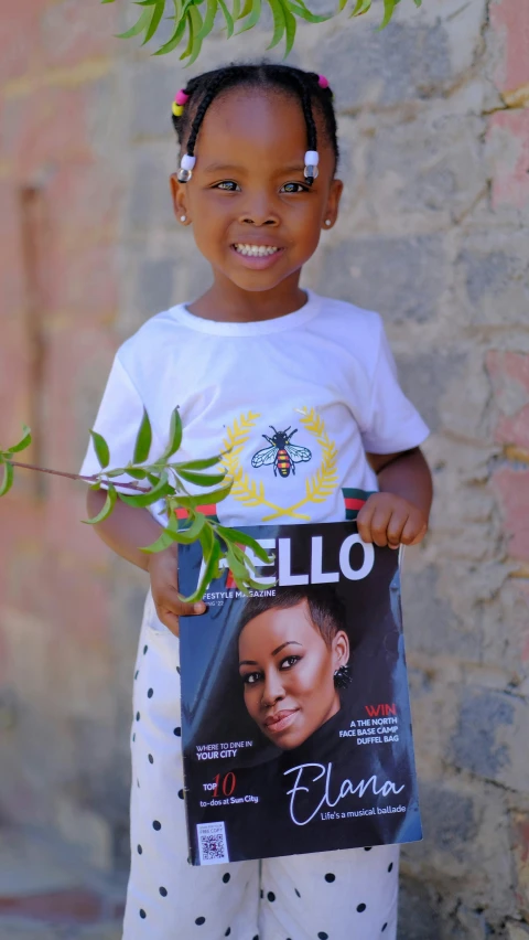 a young black girl holding a magazine with the cover of melama