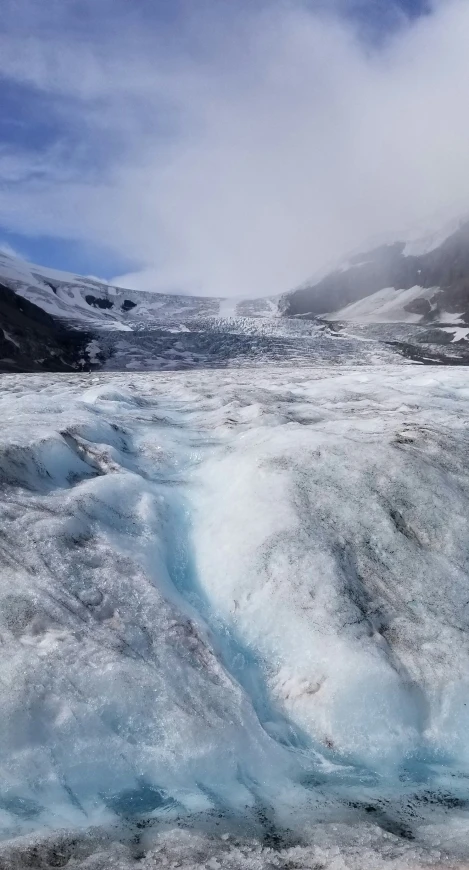 the ice is melting on the ground near a mountain