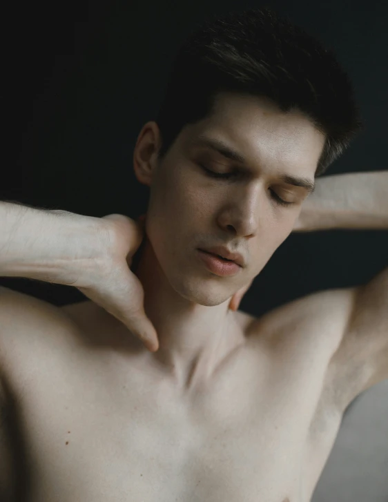 shirtless young man poses with his arm on his shoulder