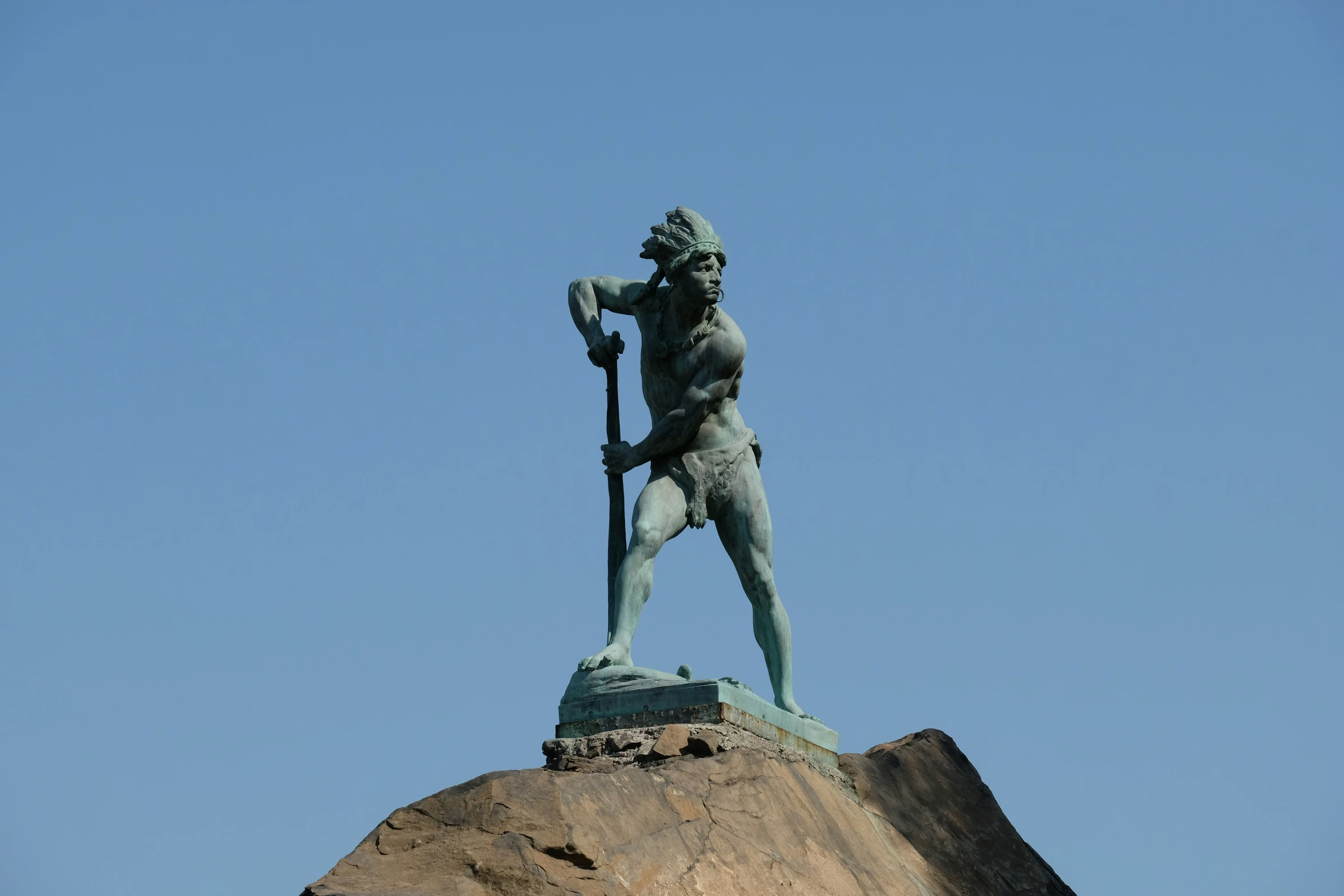 a statue of a male holding a spear on top of a hill