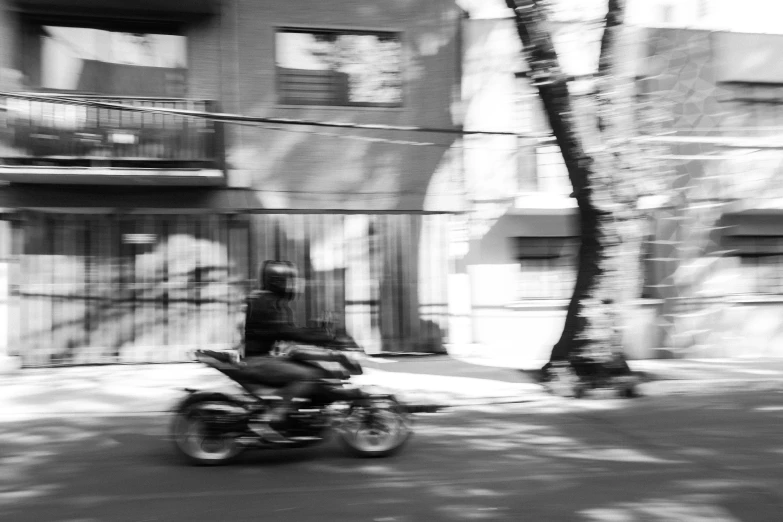 a man riding on the back of a motorcycle down a street