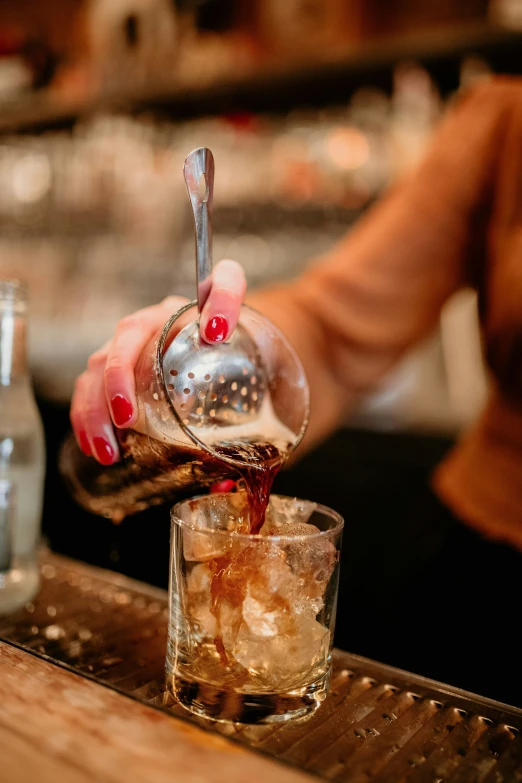 a woman is pouring ice into a glass