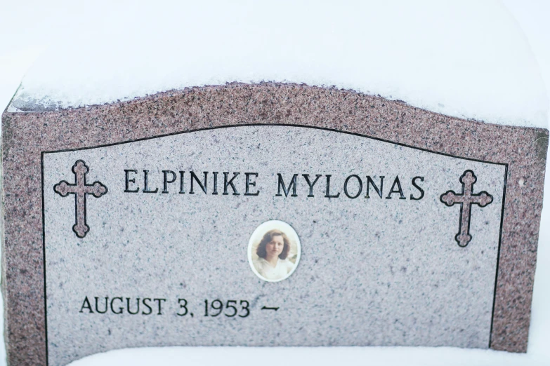 a grave marker with a picture in the snow