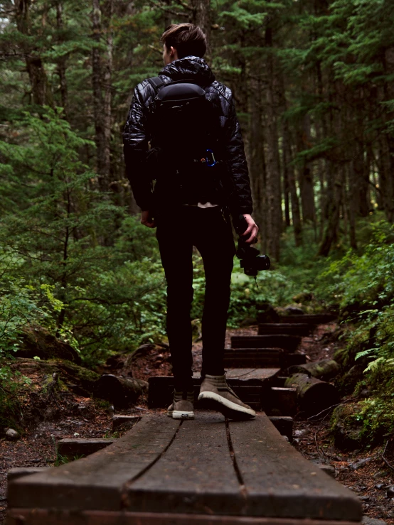 the person with backpack walks up a trail through the woods