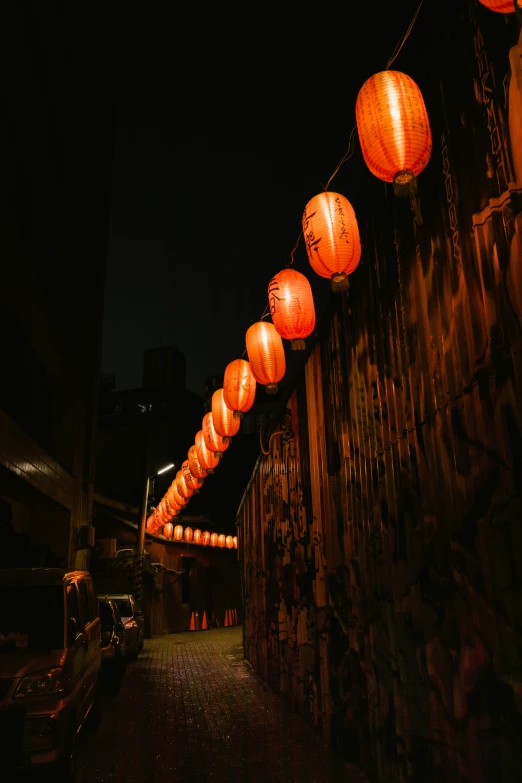 many orange lanterns strung up over an alleyway