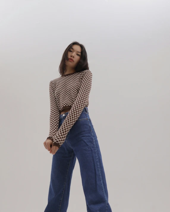 a woman in a sweater and high waisted jeans poses