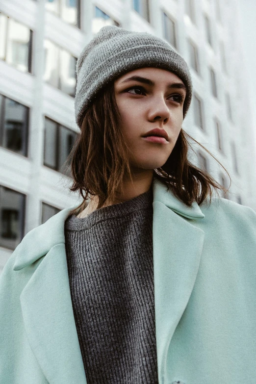 a woman wearing a hat stands in front of a skyscr