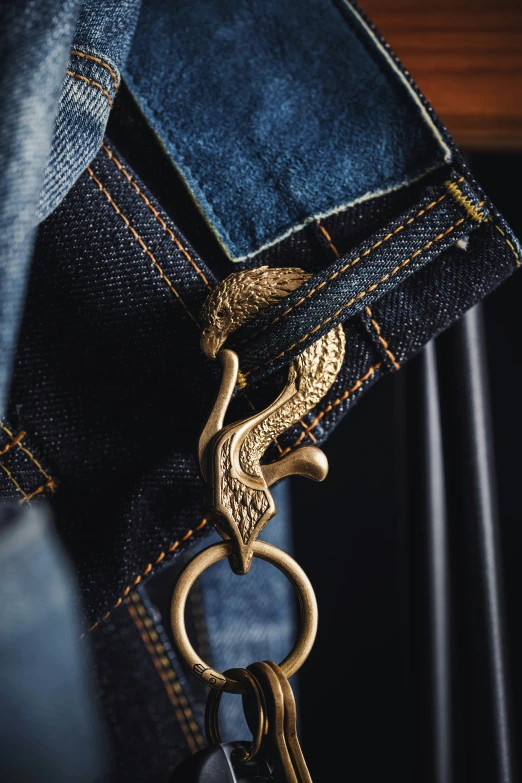 a golden snake pendant sits inside a jeans pocket