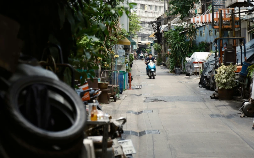 a motor scooter rides down a narrow city street