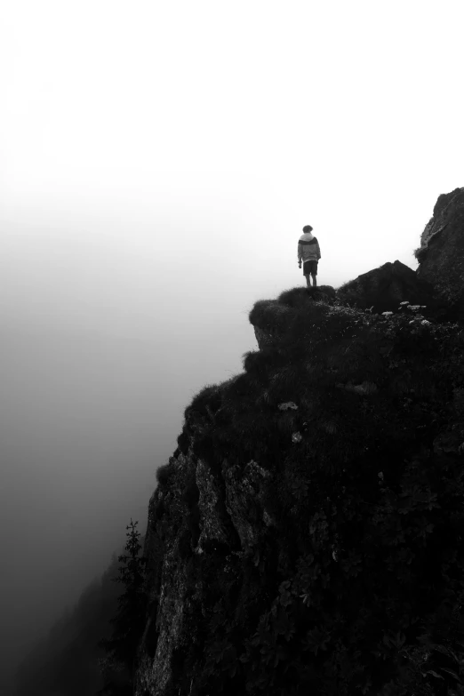 man standing on the edge of a cliff in fog