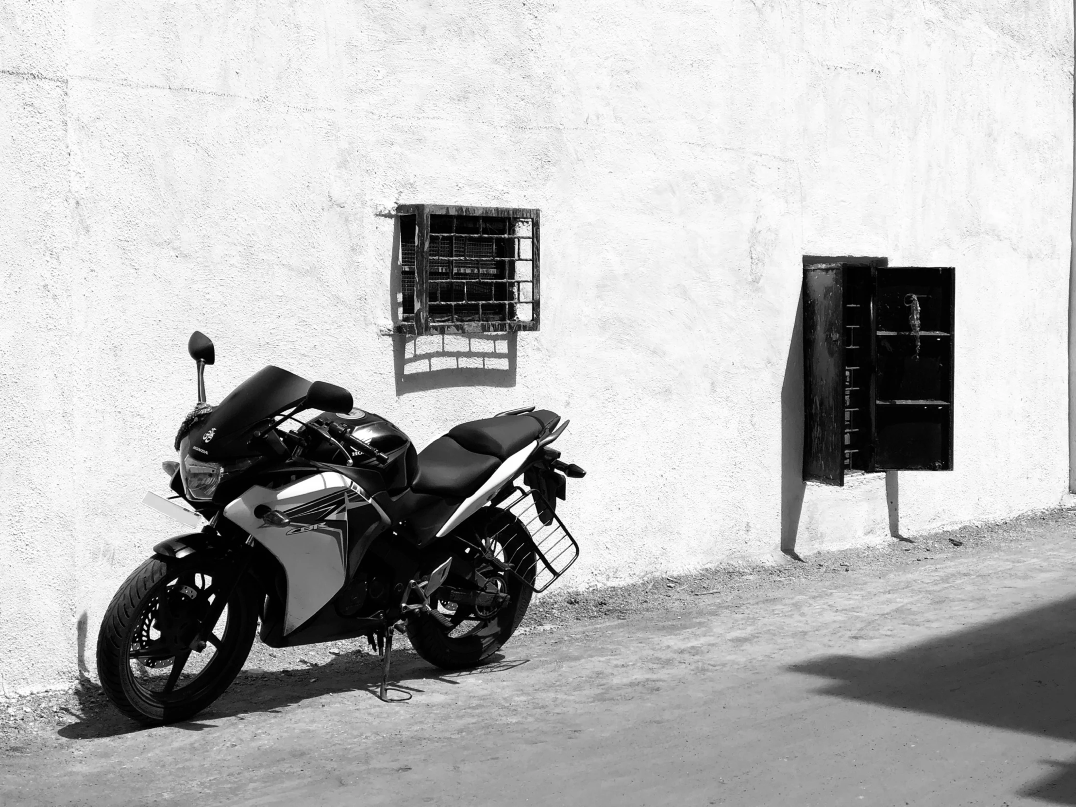 black and white pograph of a motorcycle parked outside a building