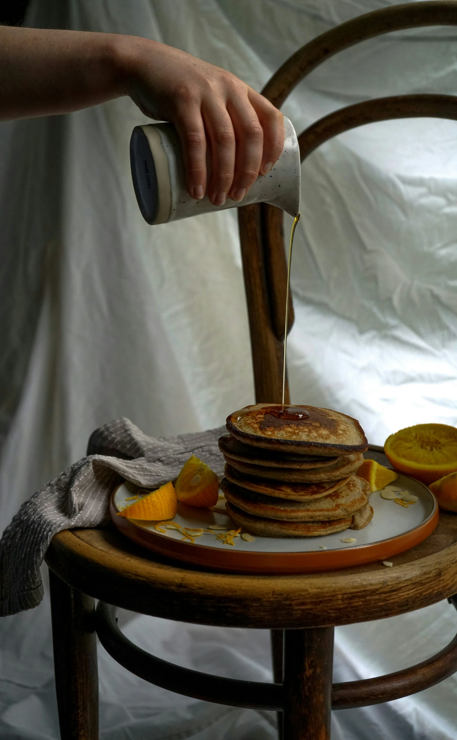 a person drizzling syrup on a stack of pancakes