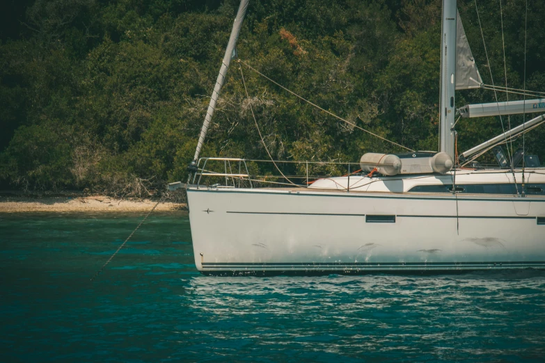 a sailboat floating in the water next to a forest