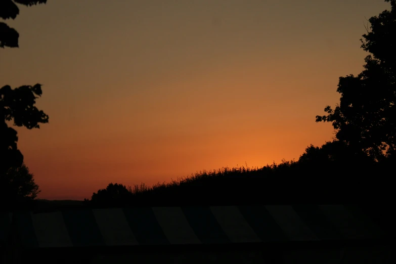 a sunset over trees with the sky in background