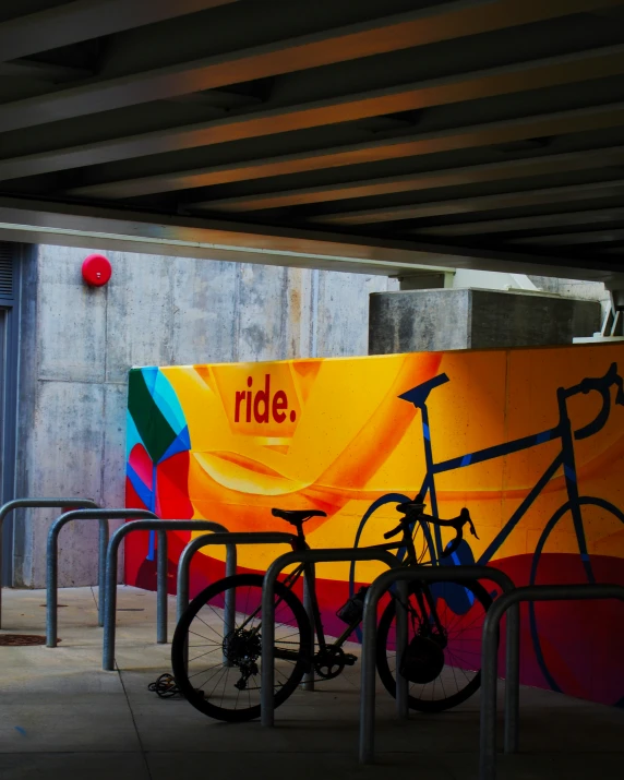 bicycles parked under a large poster near some steps