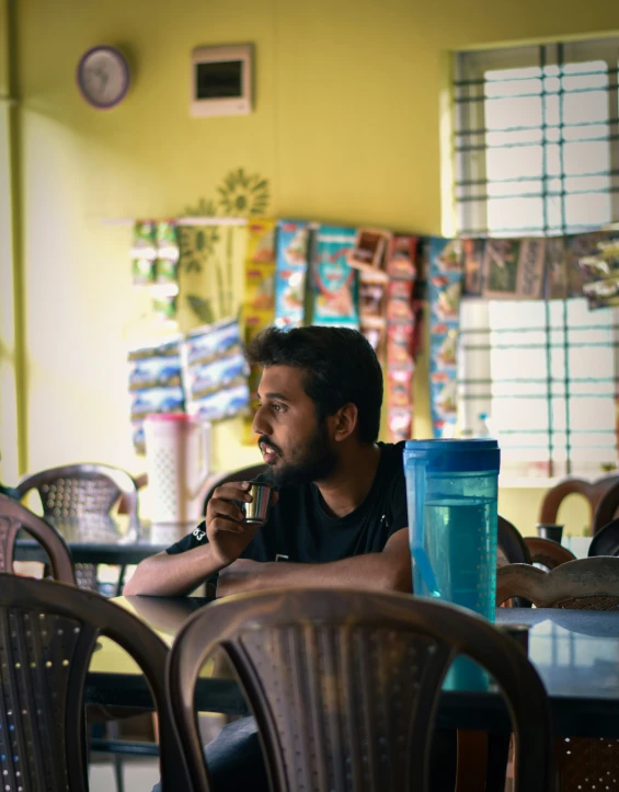 a man at a table with drinks and a paper on the wall