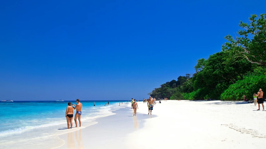 some people are walking and relaxing on the beach