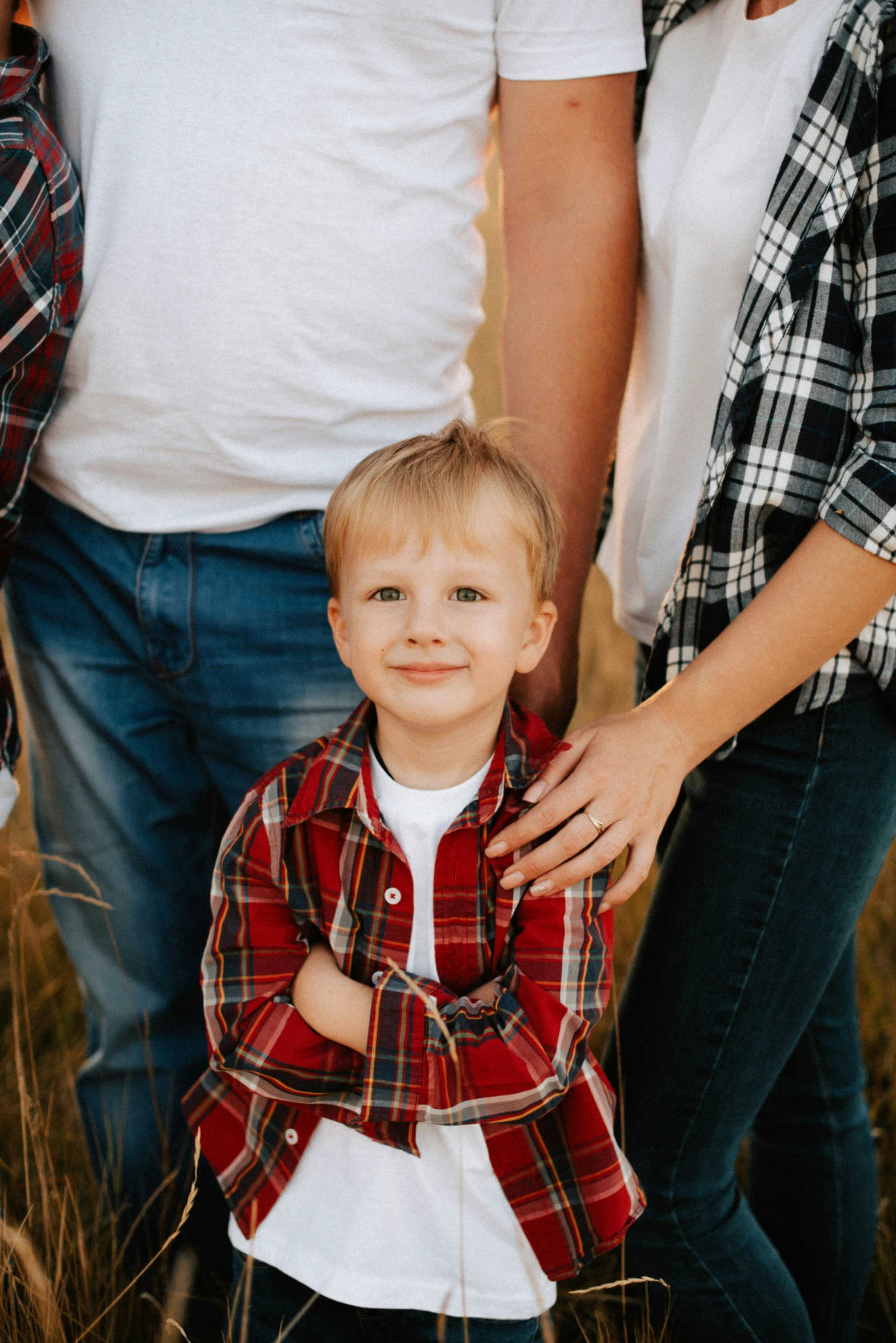 a little boy and his parents are standing in some tall grass