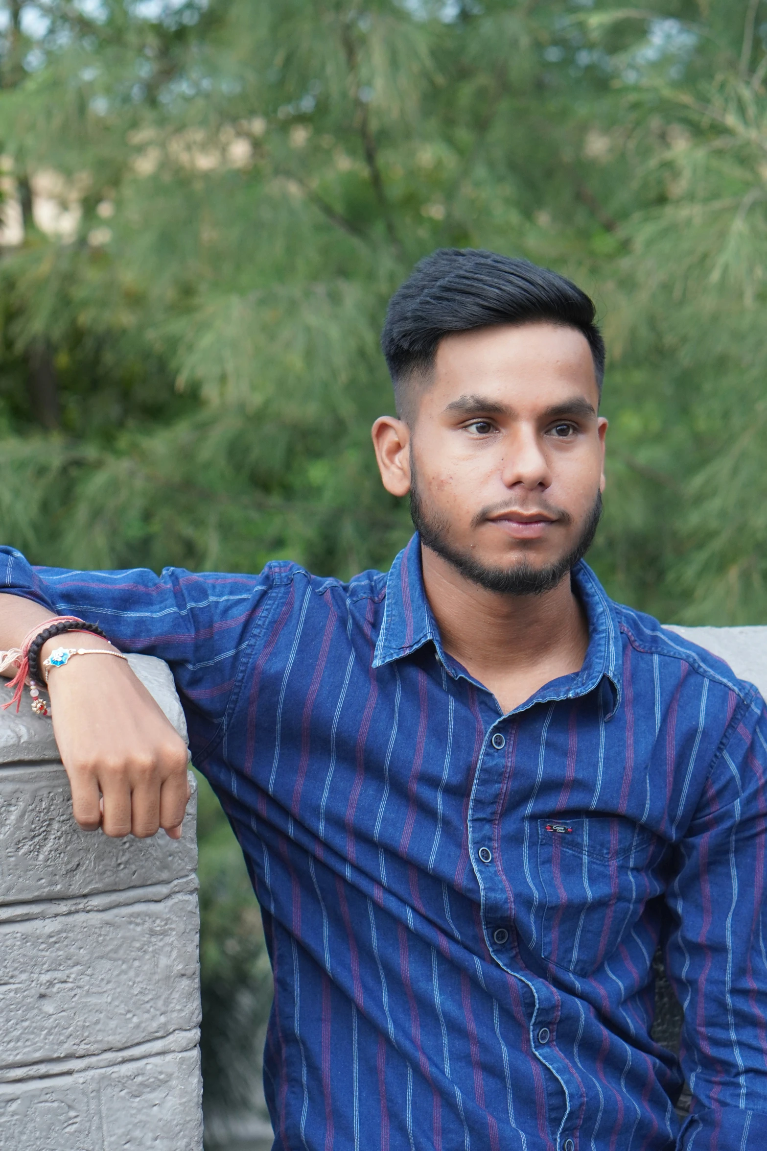 a man in a blue shirt leaning on a wall