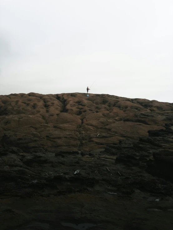 a person with a kite standing on top of a rocky hill