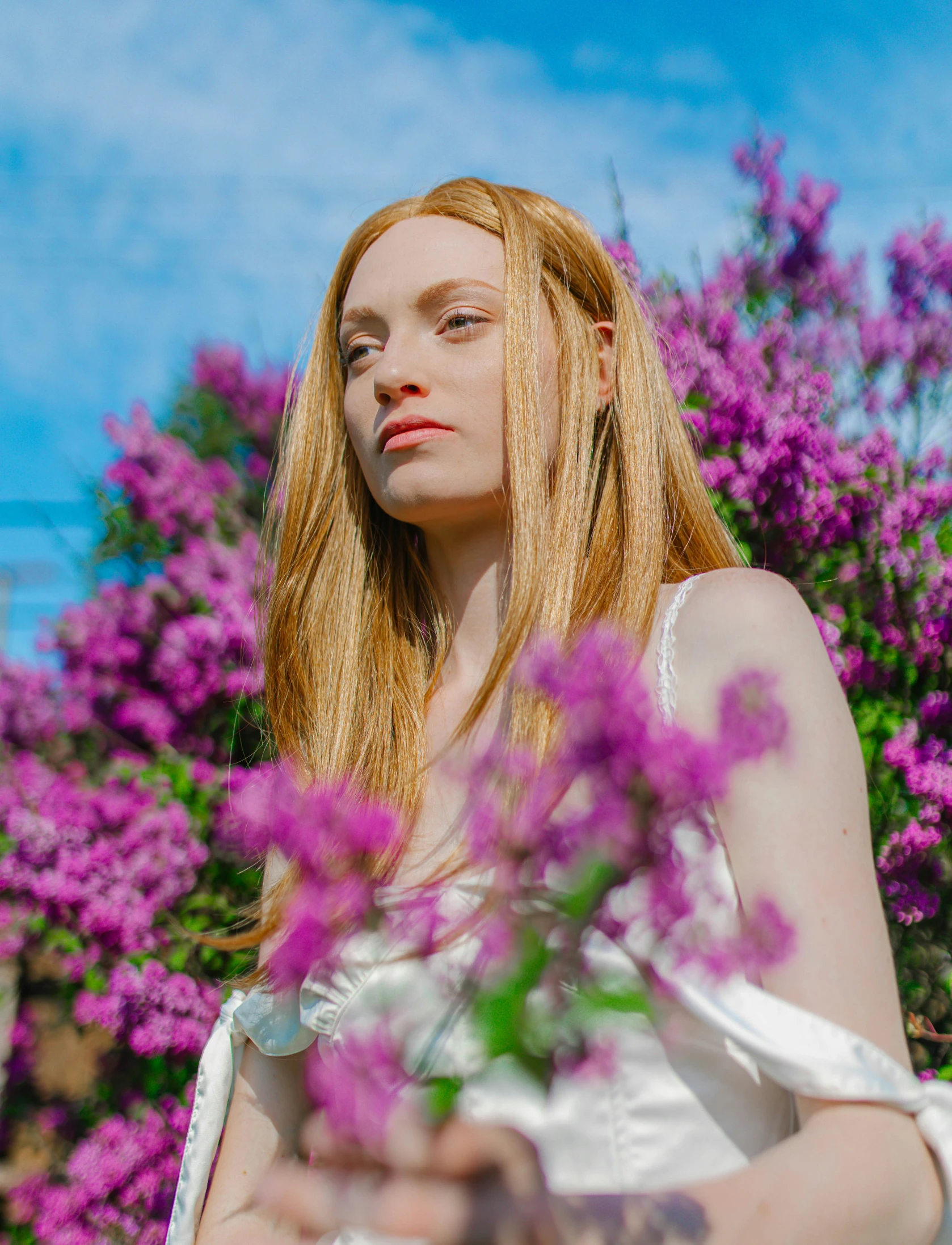 a person standing outside holding purple flowers