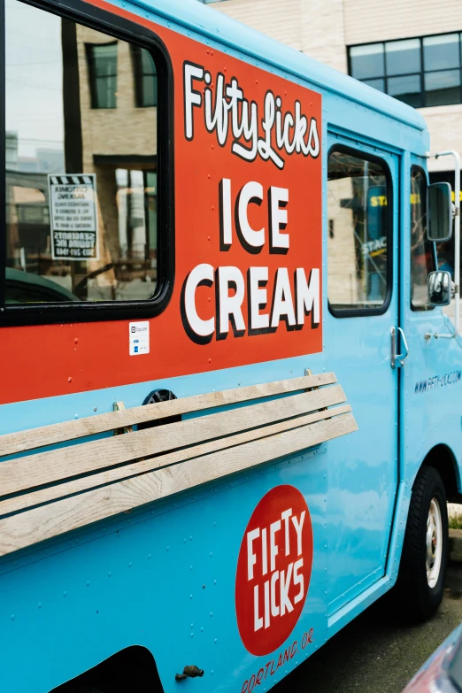 a blue and orange ice cream truck parked in front of building