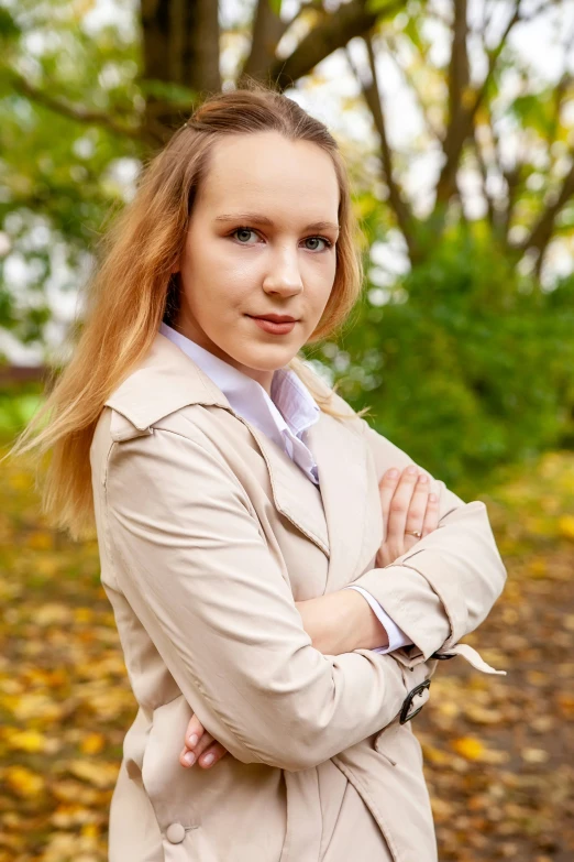 a woman wearing a trench coat posing for a picture in the fall