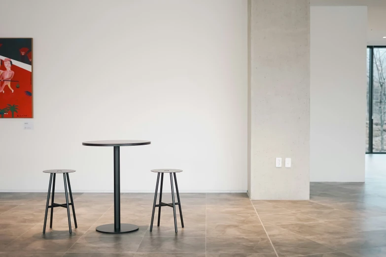 two bar stools and a round table in an empty room