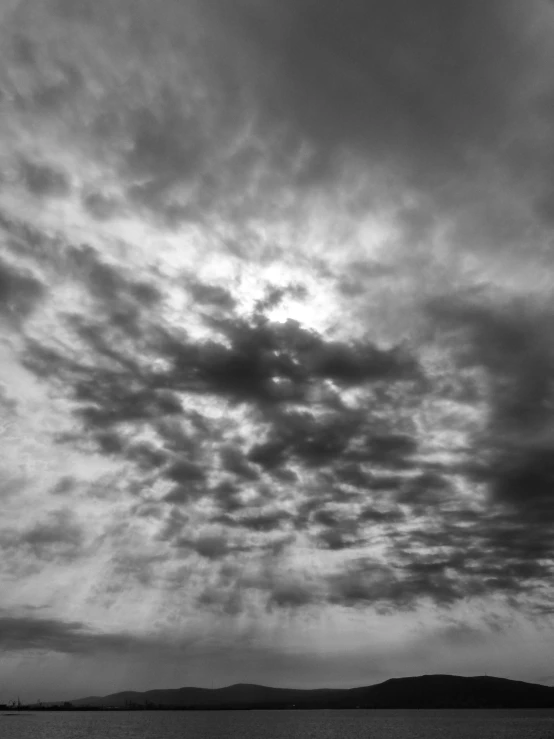 black and white pograph of the cloudy sky above a calm sea