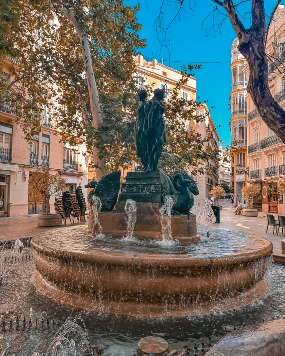 a small fountain in a city park filled with people