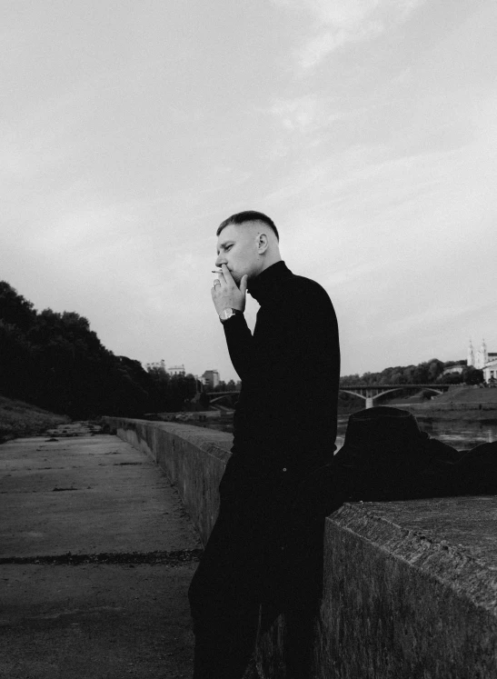 a man stands near the side of the road and smokes a cigarette