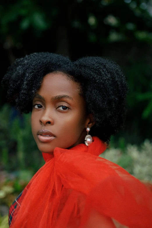 a close - up of a person wearing an orange shawl, with green trees in the background