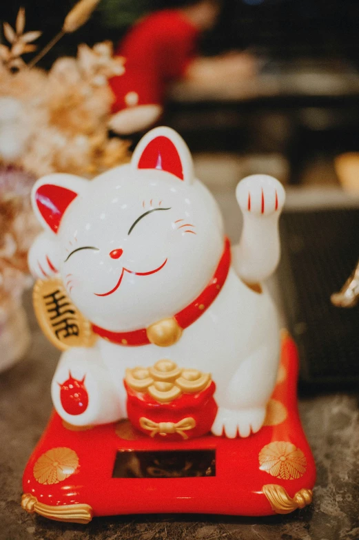 a lucky cat figurine that is red and gold