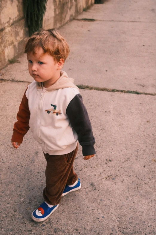 a small boy wearing a red and white shirt and blue shoes