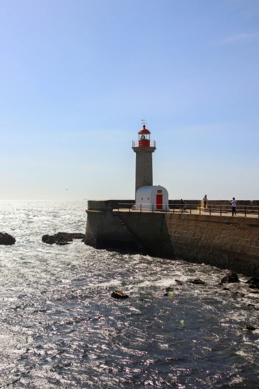 a large gray and red light house over looking the ocean