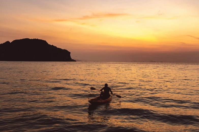 a person riding in a canoe with a sunset in the background