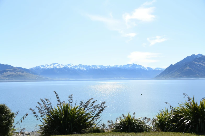 water, trees and mountains are at the end of a large lake