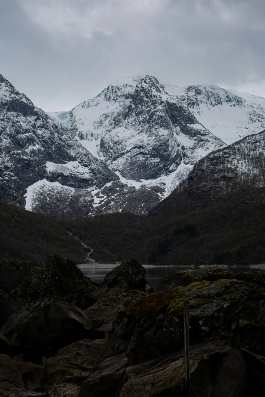 the snow covered mountains stand behind the rocky outcropping