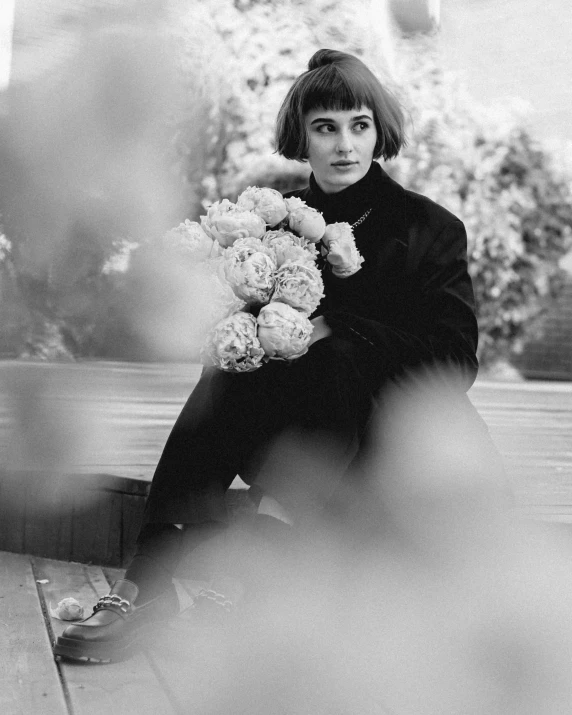 a woman sitting on the ground and holding flowers in front of her