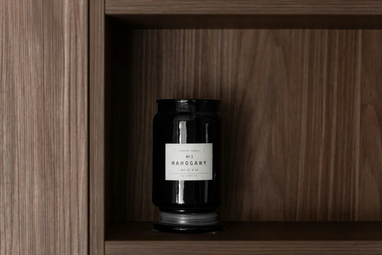 a wooden shelf filled with black candle and a label