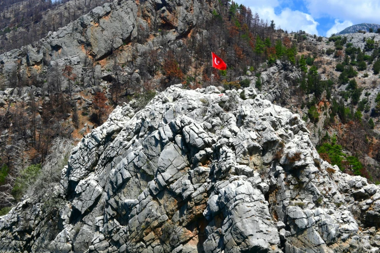 a man holding a red kite on top of a rocky mountain